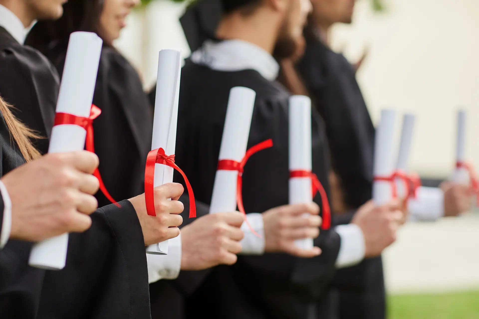 Estudiantes sosteniendo sus diplomas de grado