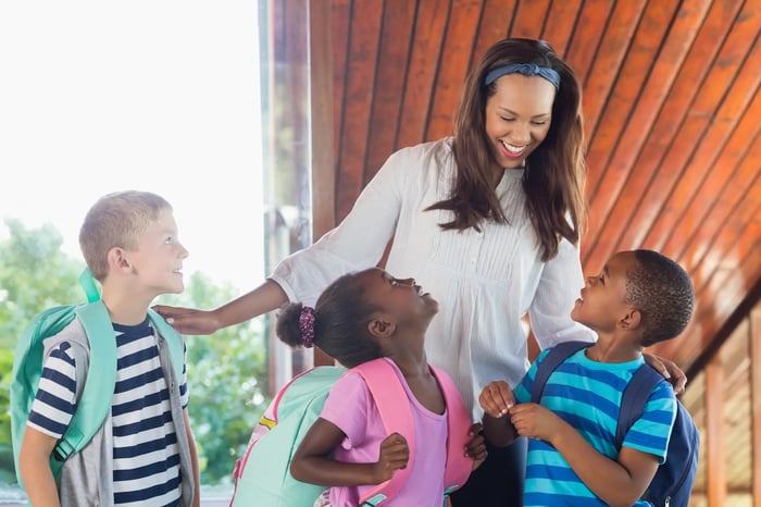 Profesora sonriente junto con tres niños