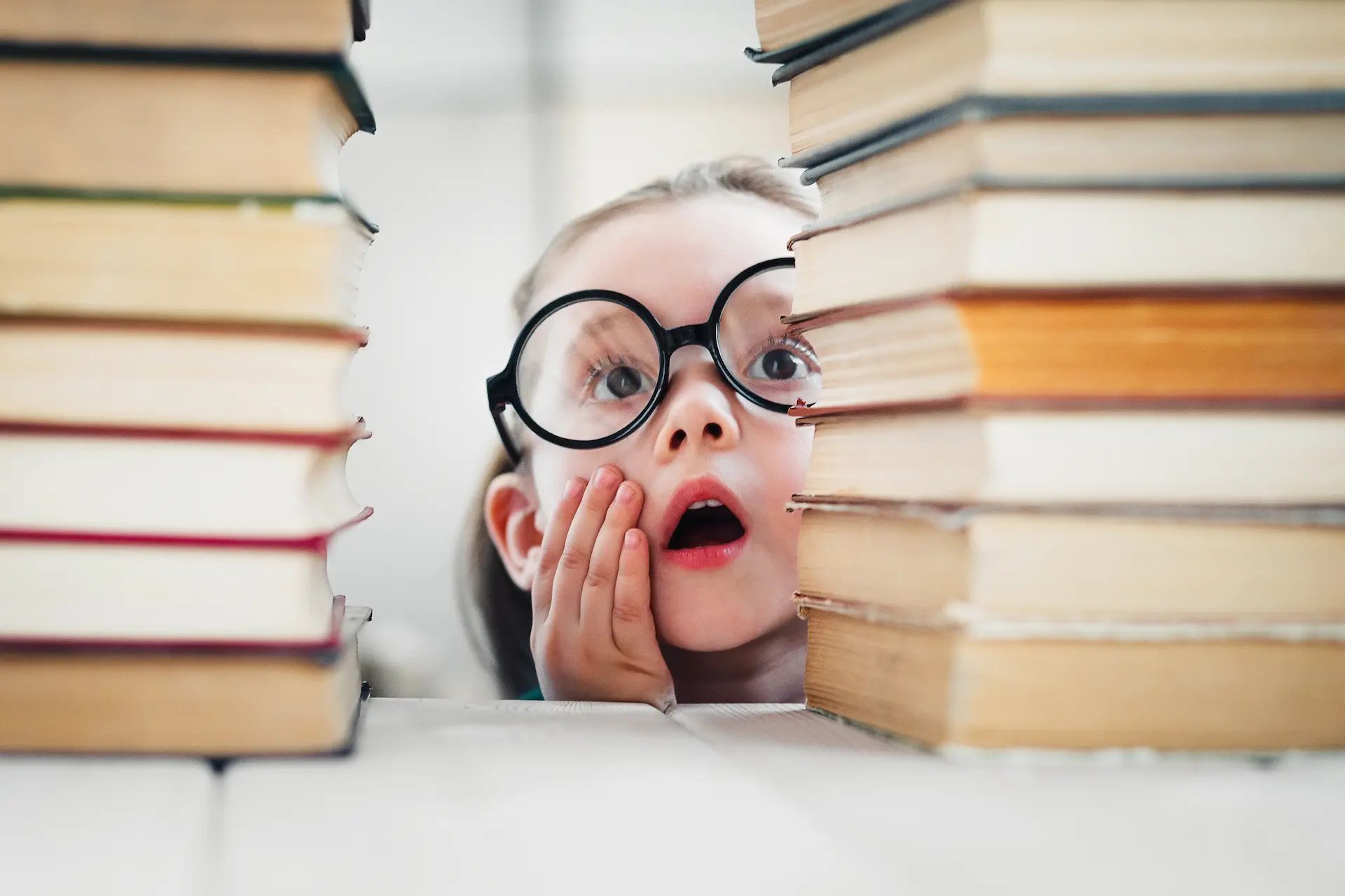 Niña sorprendida viendo varios libros