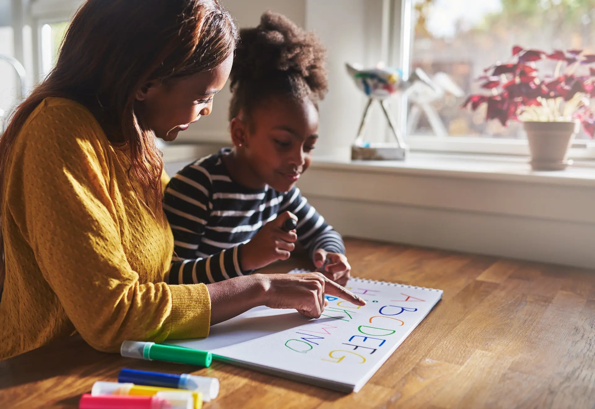 Mujer enseñando el abecedario a una niña