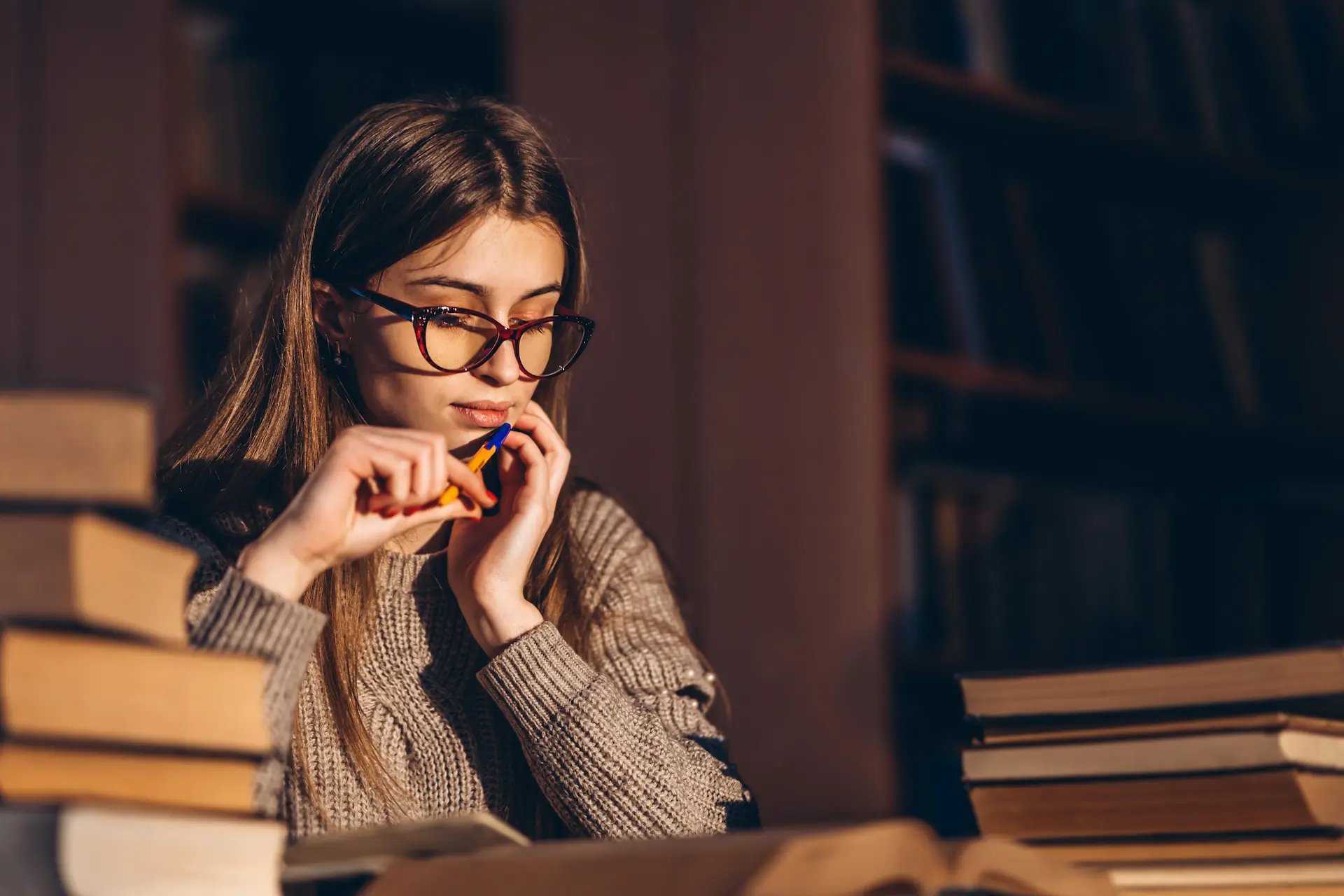 Mujer estudiando junto con varios libros en su mesa